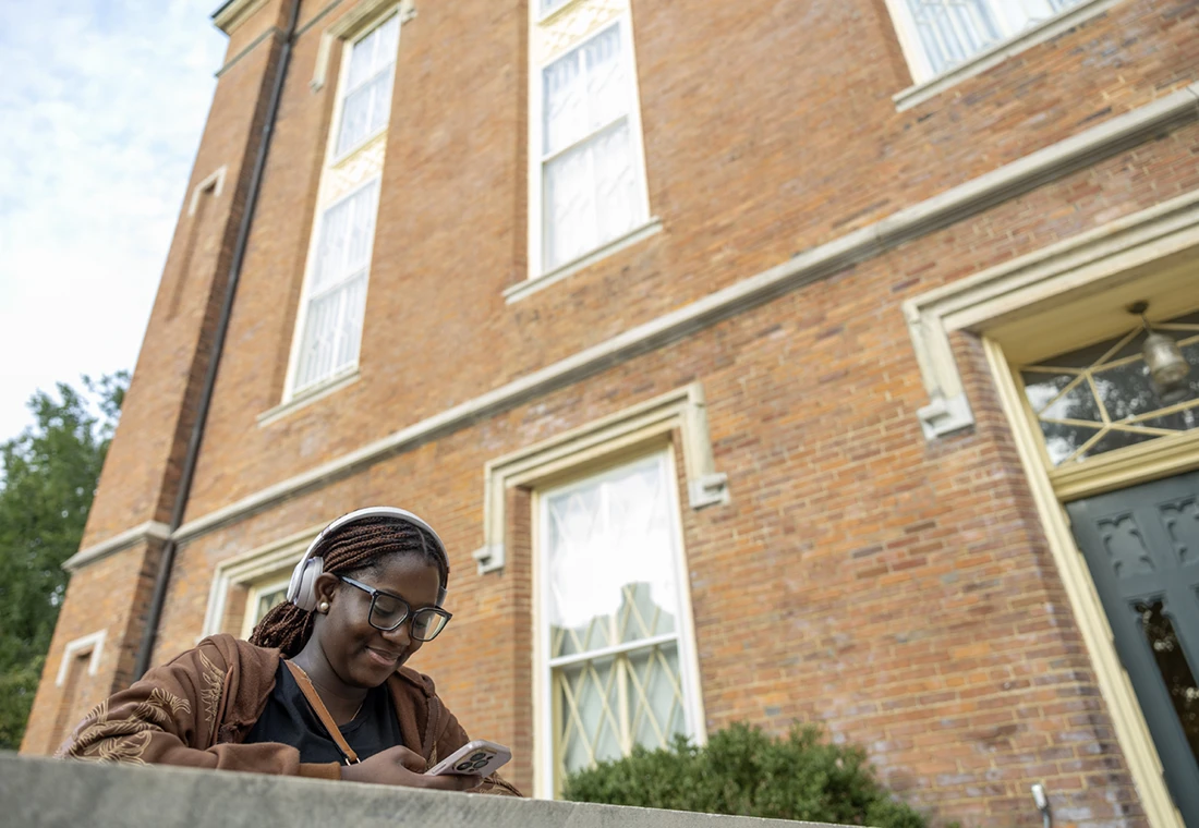 A Knox students smiles at her cell phone outside of Old Main.