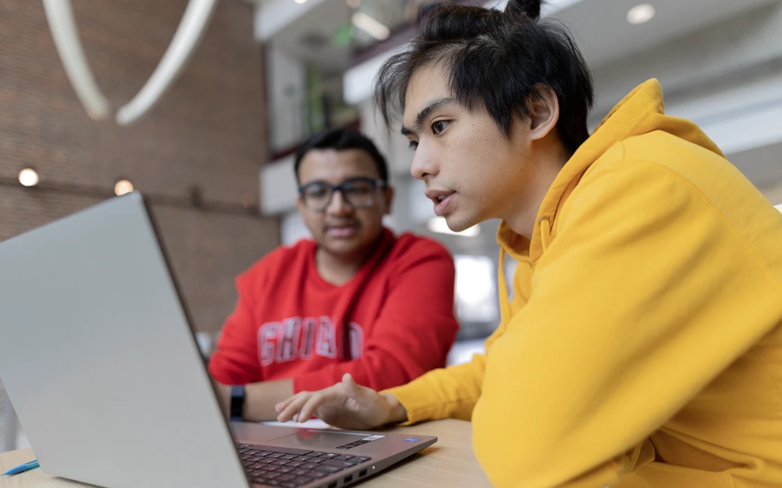 Two Knox students sit in front of a laptop underneath at whale skeleton in Knox's Umbeck Science Mathematics Center.