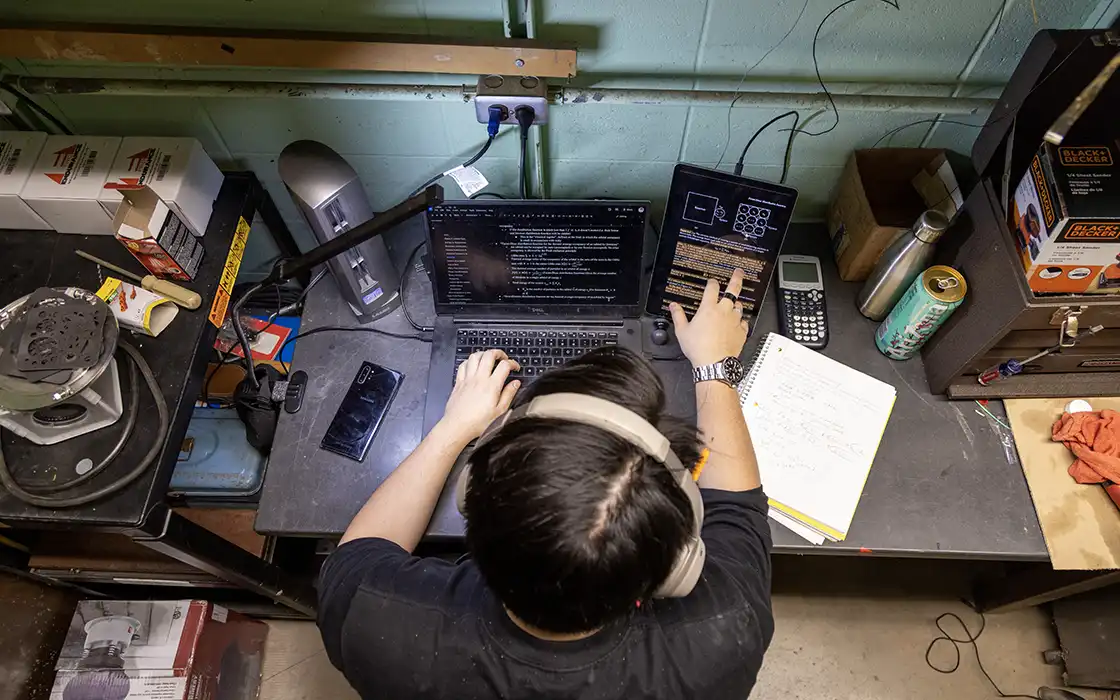 A student sits at a table with technical equipment in front of them.