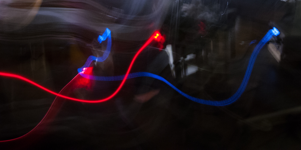 Blurred tracks from a red laser and blue LED data display in a physics lab.