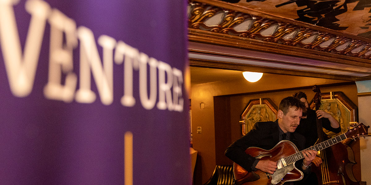 A Venture Boldly banner stands next to a band playing.