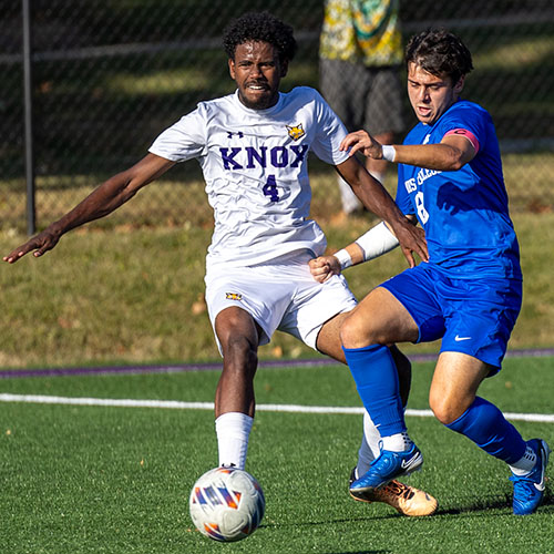 Two soccer players going for the soccer ball.