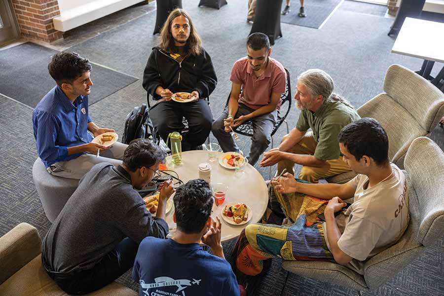 A group of students sitting around a table with a professor. 