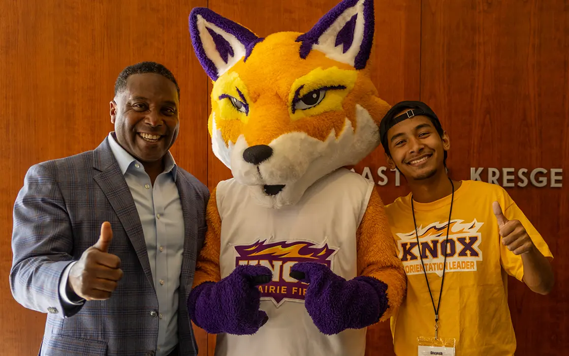 President McGadney gives a thumbs up as he posted with Blaze, the Knox fox mascot, and a student.