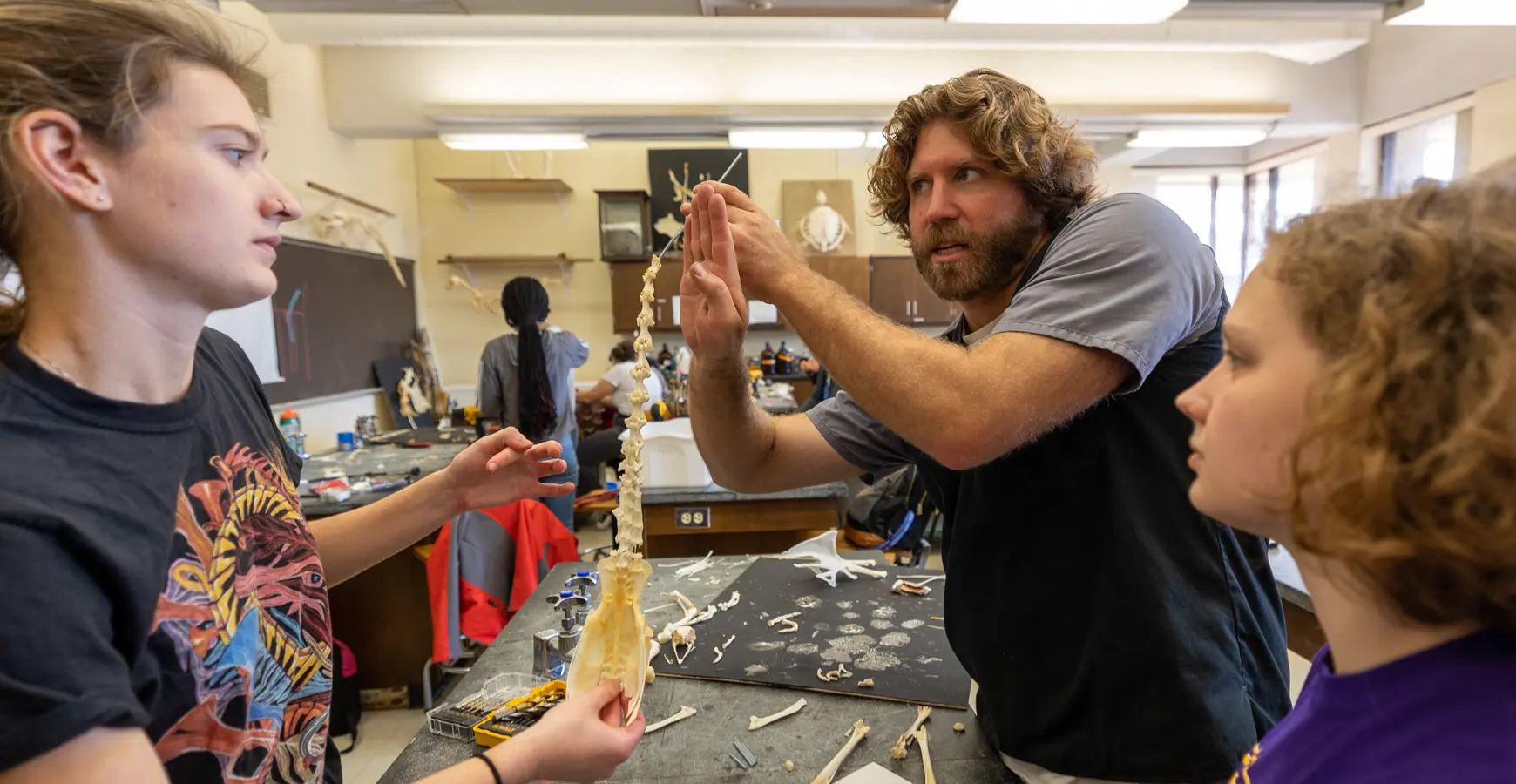 Professor Nicholas Gidmark talks with students over a laboratory table.