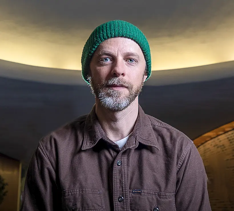 Casey Foubert looks at the camera and smiles. He wears a green knit cap.