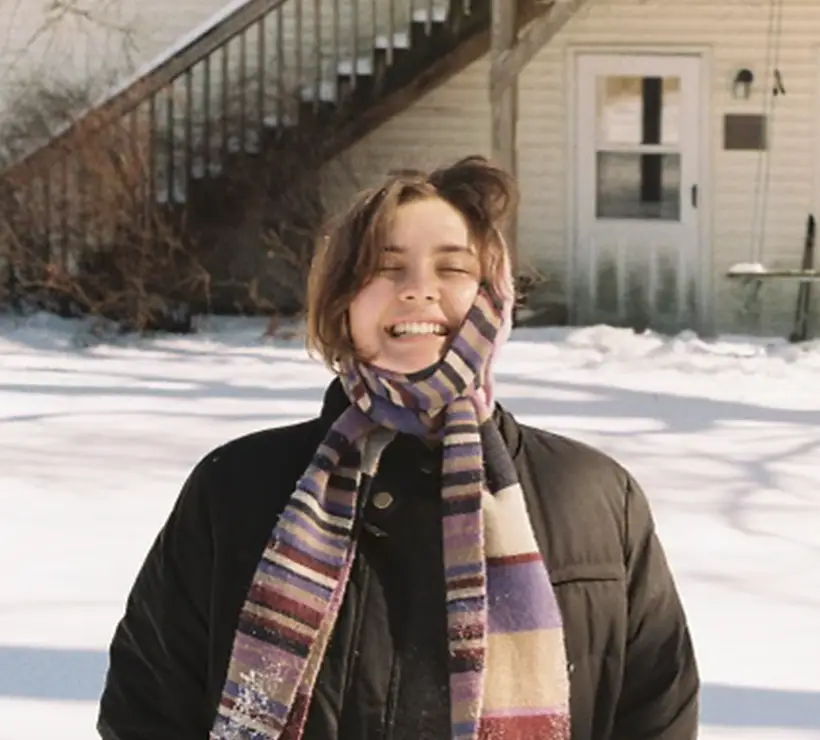 Brooke Bellmar, wearing a winter coat and scarf wrapped around her head, smiles at the camera.
