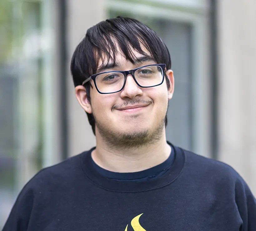 Josh Carlos smiles in front od a window.