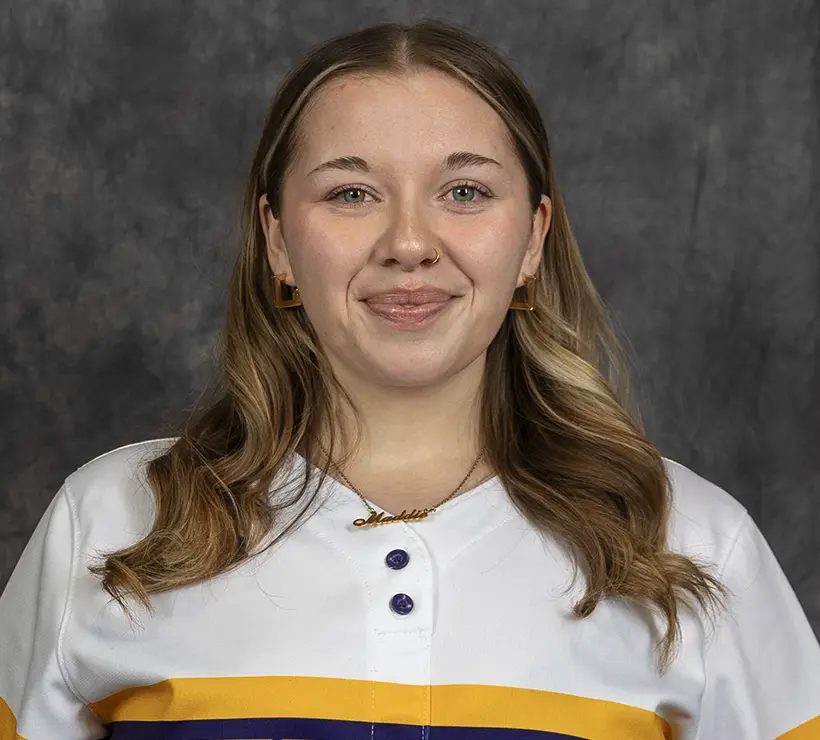 A headshot of Maddie Hicks, who is smiling in front of a geay background.