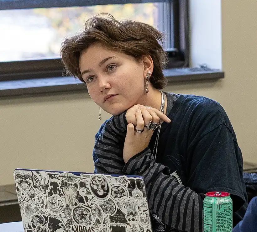 Mar Armstrong sitting at a desk next to a window, staring ahead resting on a hand.