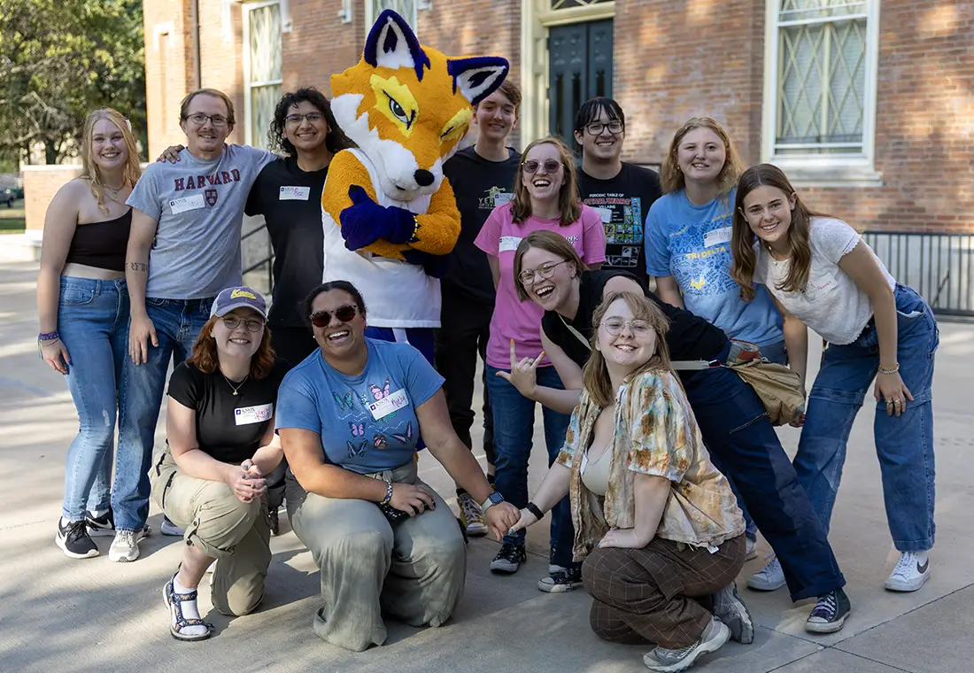 A group of students stand outside Old Main with Blaze.