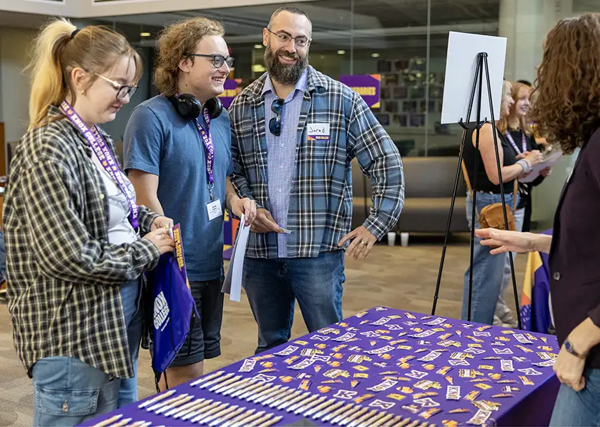 A family stands in front of a table with Knox stickers and pens at an open house event.