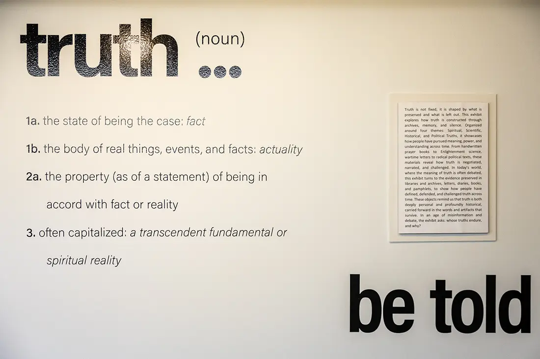 The word truth appears in bold, black letters on a white wall. Below it are the words be told. The definition of truth on the wall as well.