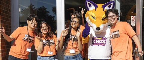 Four students pose with a fox mascot.