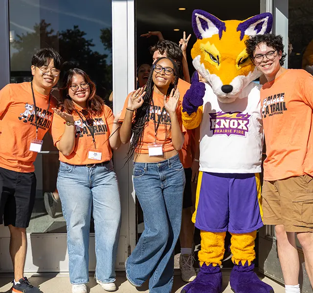 Four students pose with a fox mascot.