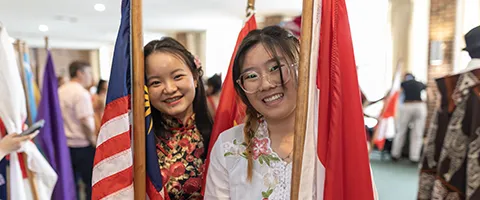 Two Knox international students smiling and holding the flags of the United States and Dhina