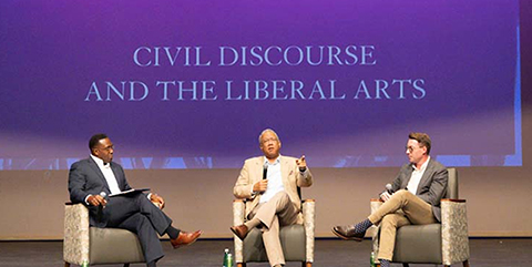 Three sitting on a stage people on a stage having a discussion in front of a backdrop that says Civil Discourse and the Liberal Arts.