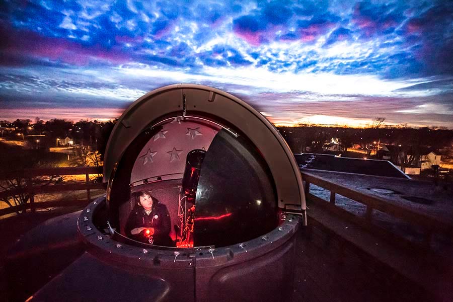 Physics faculty Nathalie Haurberg with telescope and dome at observatory on top of the Umbeck Science and Math Center.
